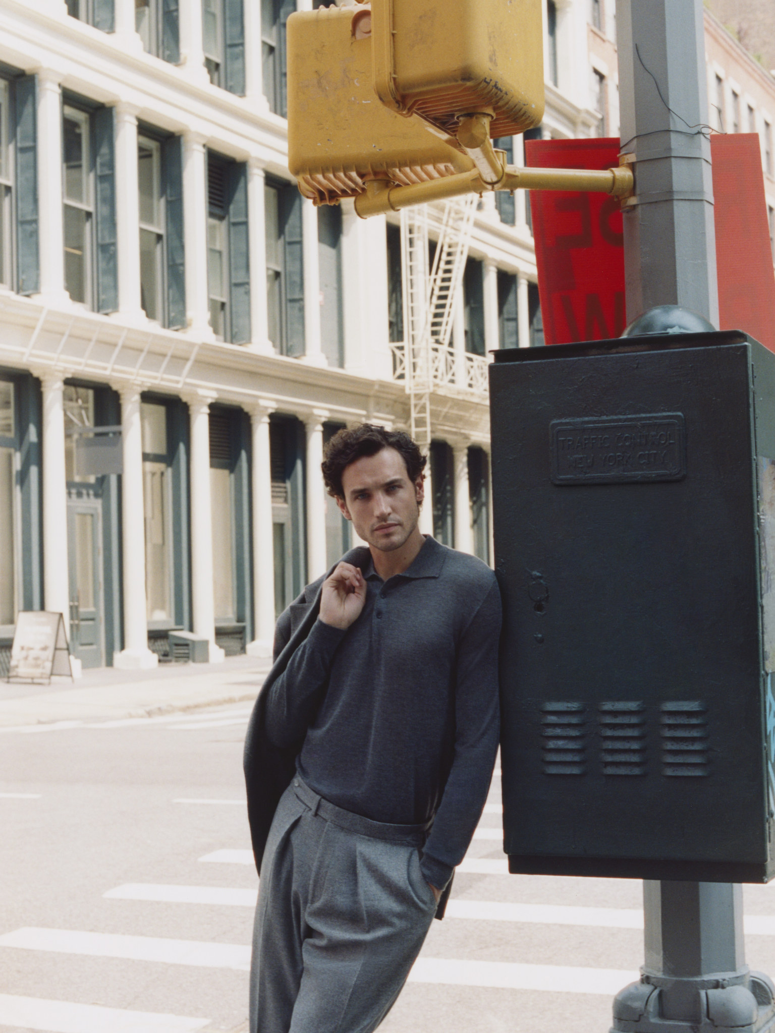 Male model in a dark Clements+Church knitted polo and grey trousers on a New York street