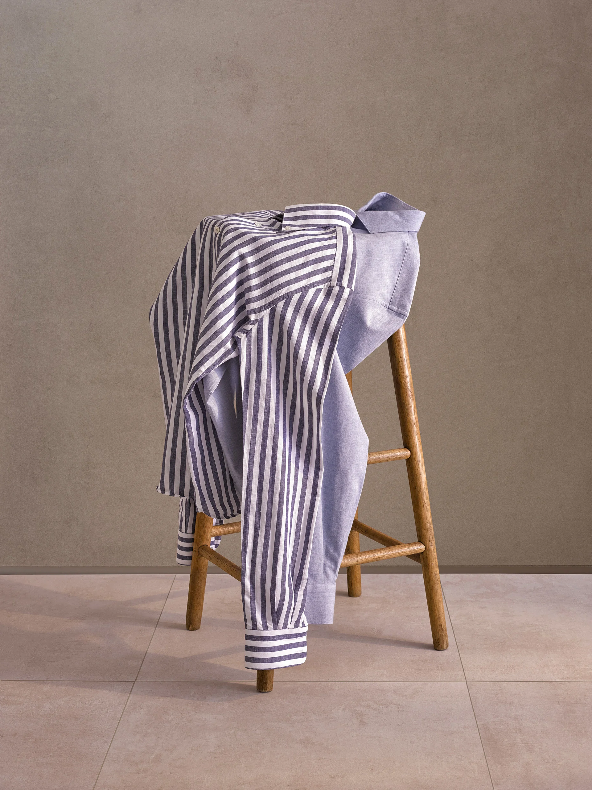 Striped shirt and plain shirt draped over a wooden step stool
