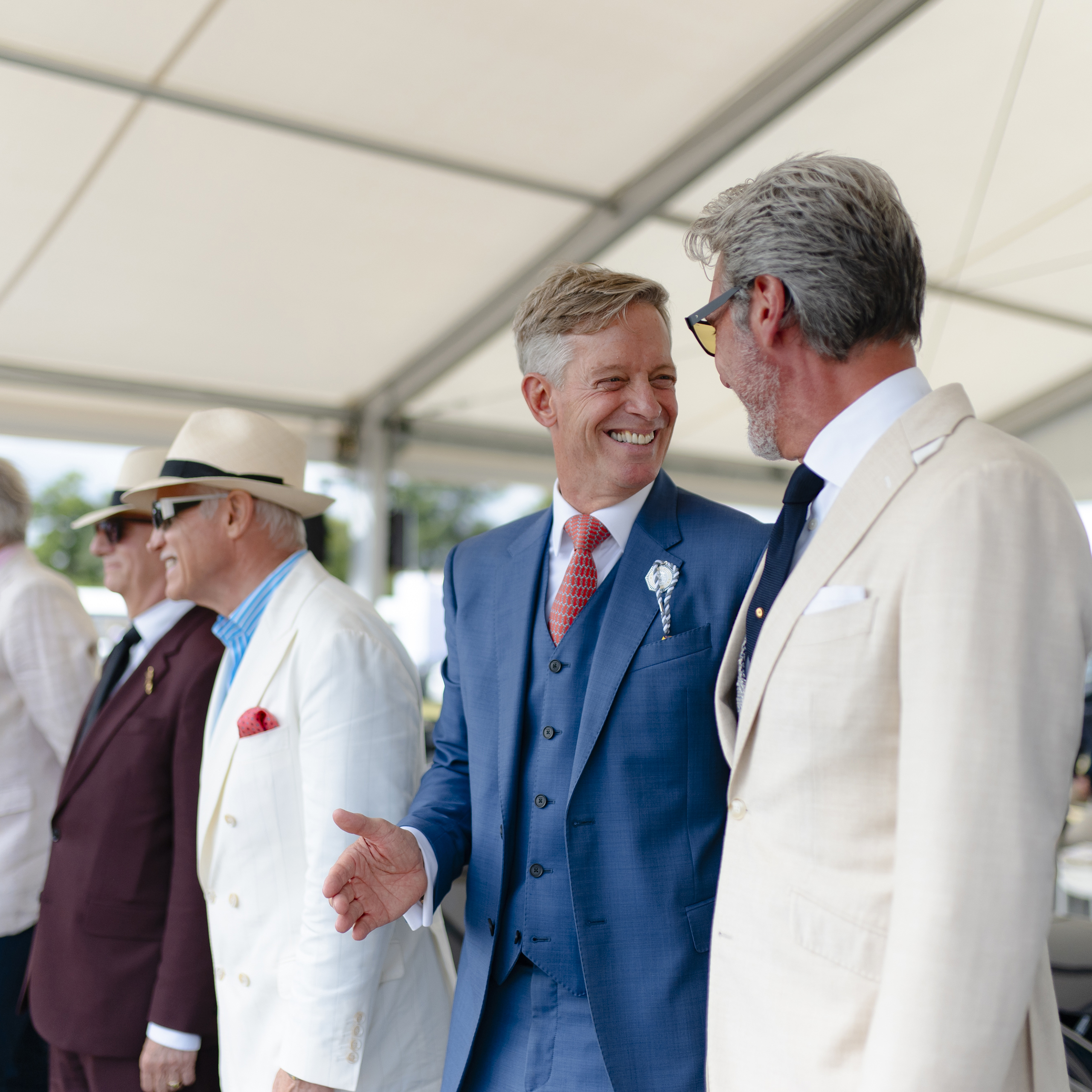 Two guests in tailored jackets sharing a moment under the Salon Privé event marquee