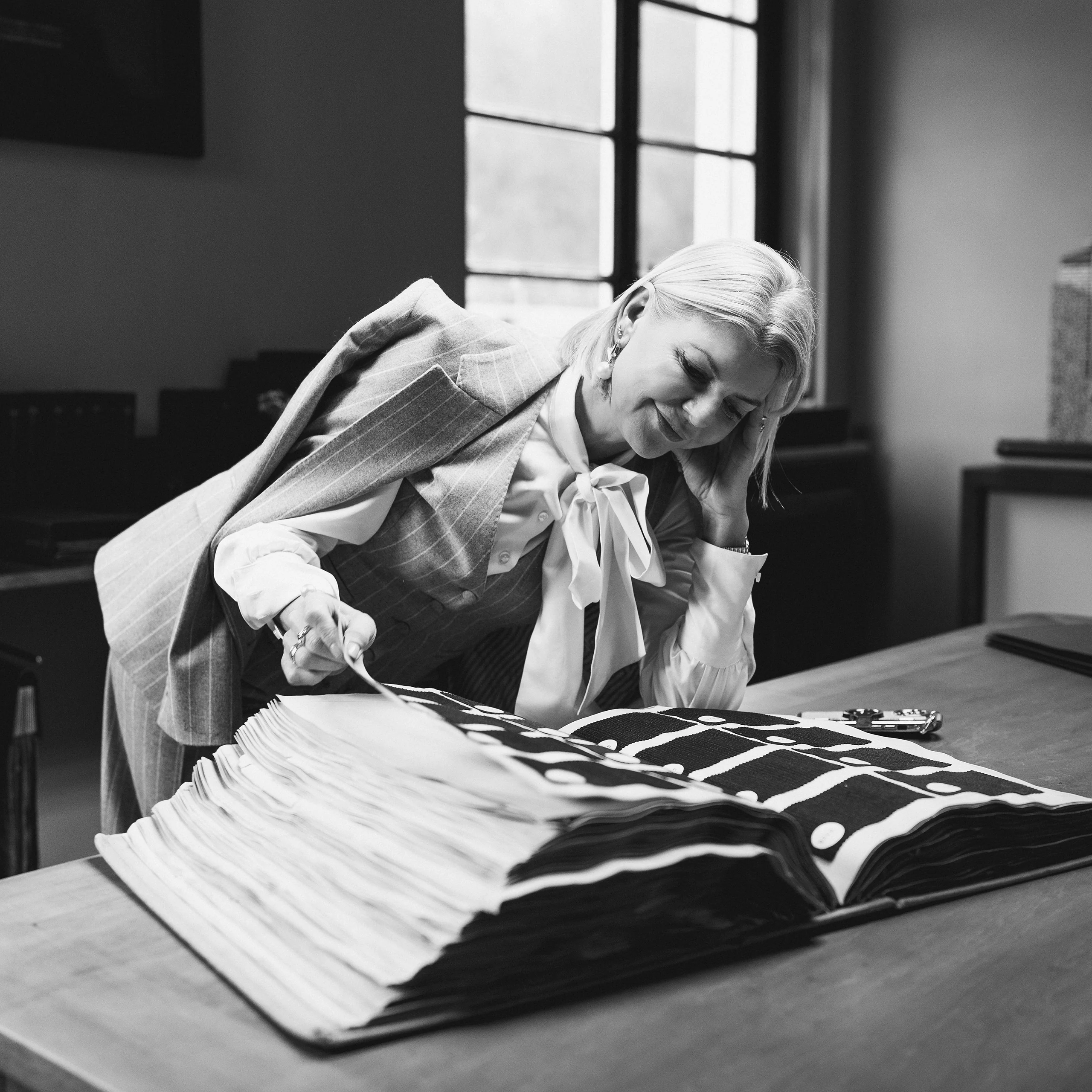 Black-and-white photograph of pattern cutting on an Italian tailoring bench