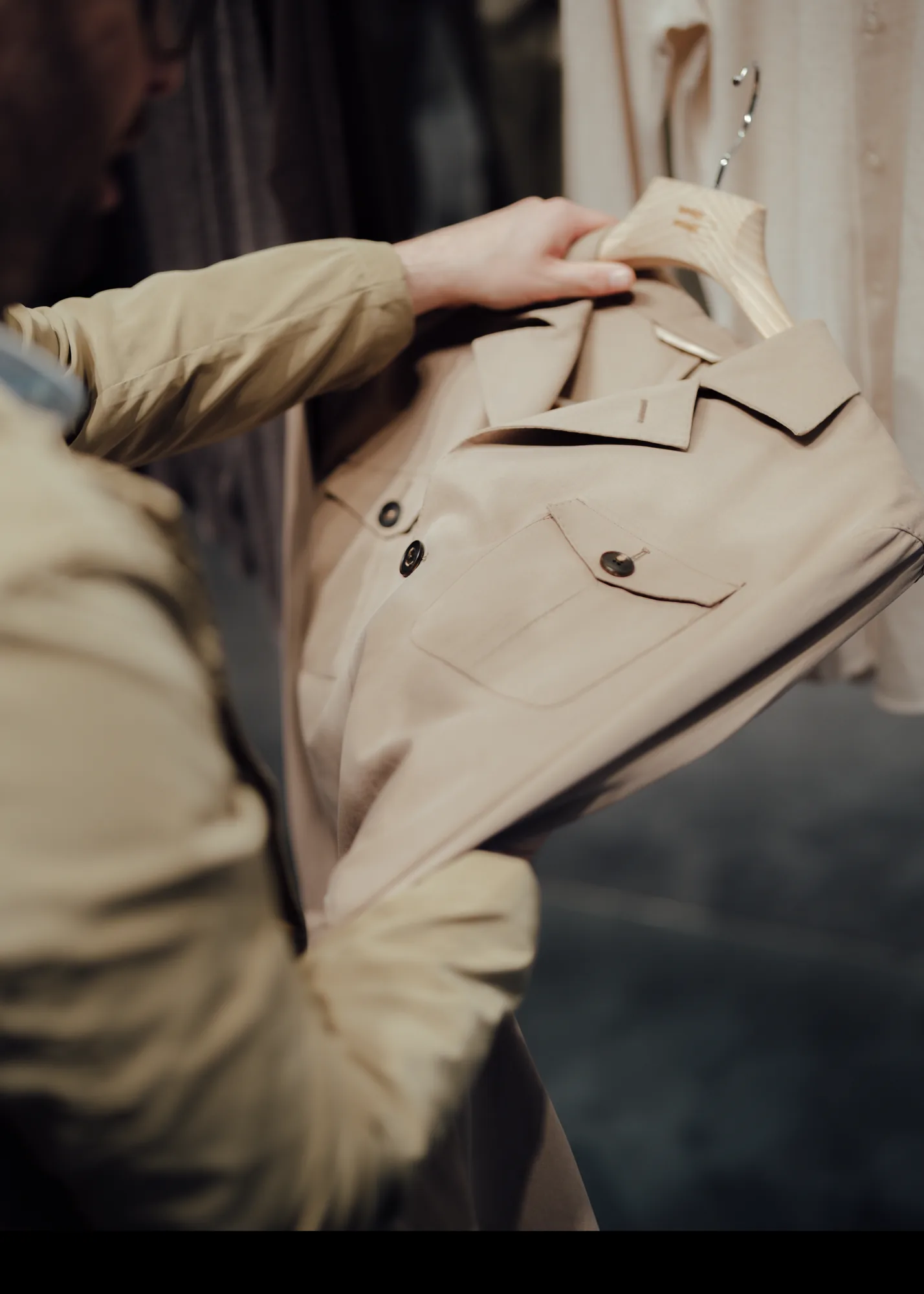 Client holding a finished stone-coloured Clements and Church overshirt on a wooden hanger at the Albemarle Street pop-up