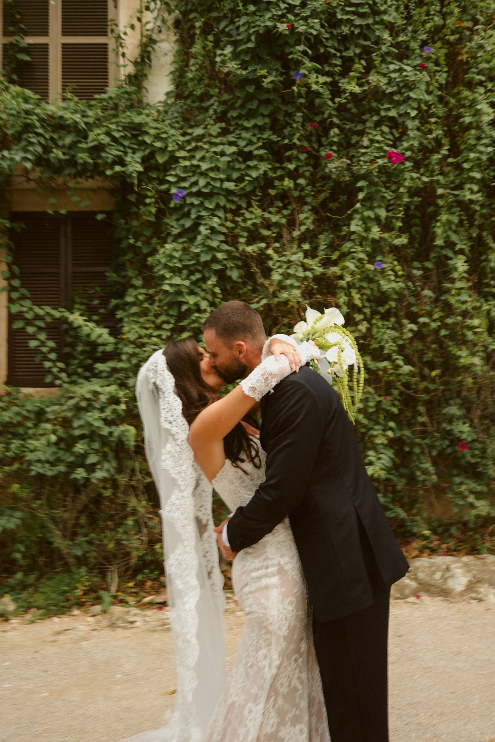 Rebekah and Brad kissing in front of an ivy-covered wall