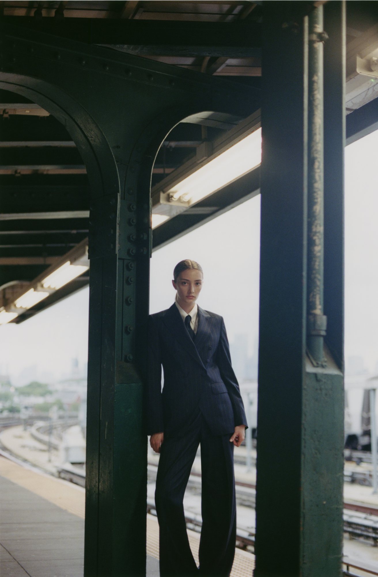 Woman in a custom made navy and brown Carnet pinstripe double-breasted trouser suit on a Brooklyn subway platform