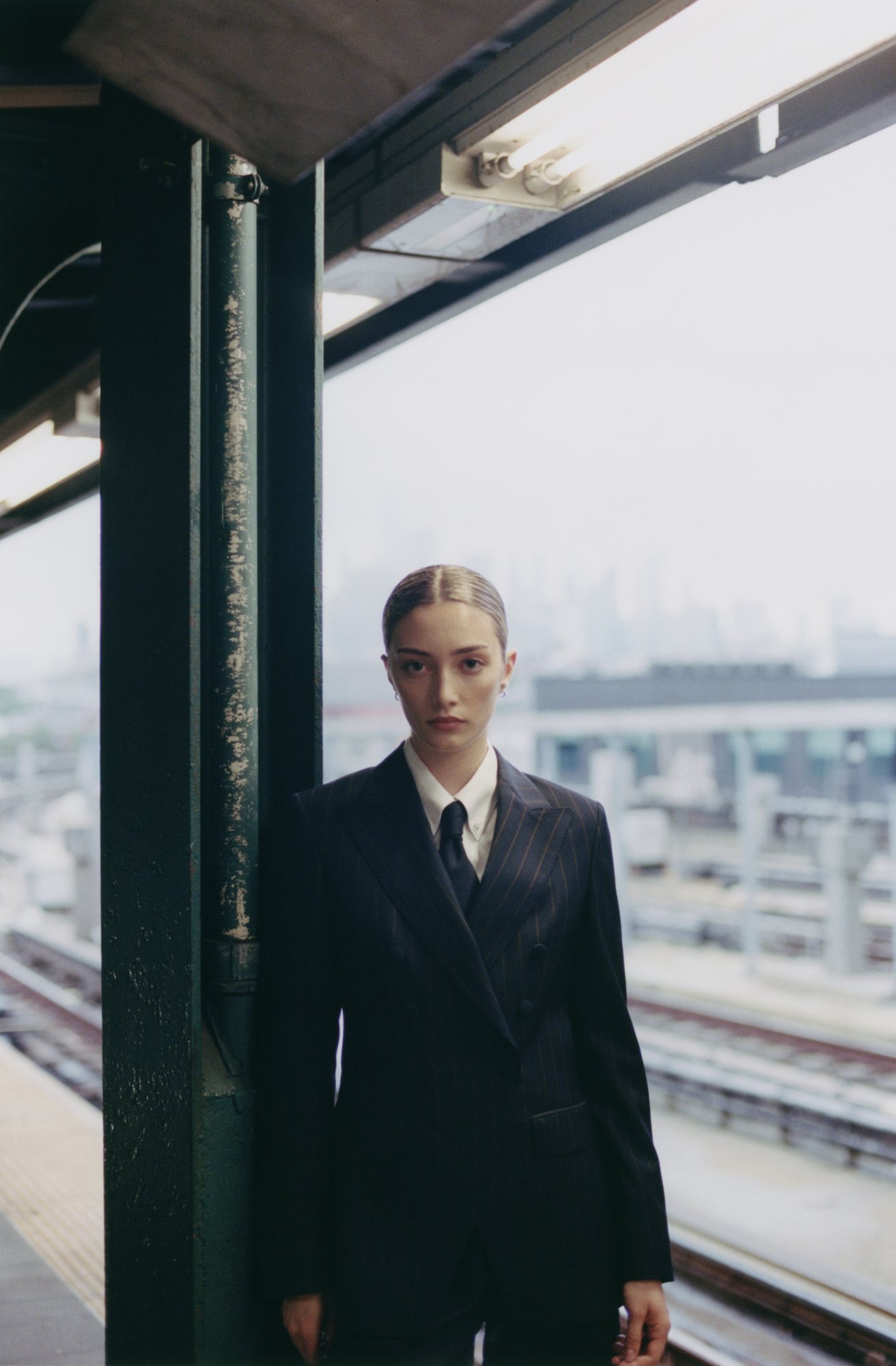 Woman in a custom made navy and brown pinstripe double-breasted jacket, white shirt and navy tie